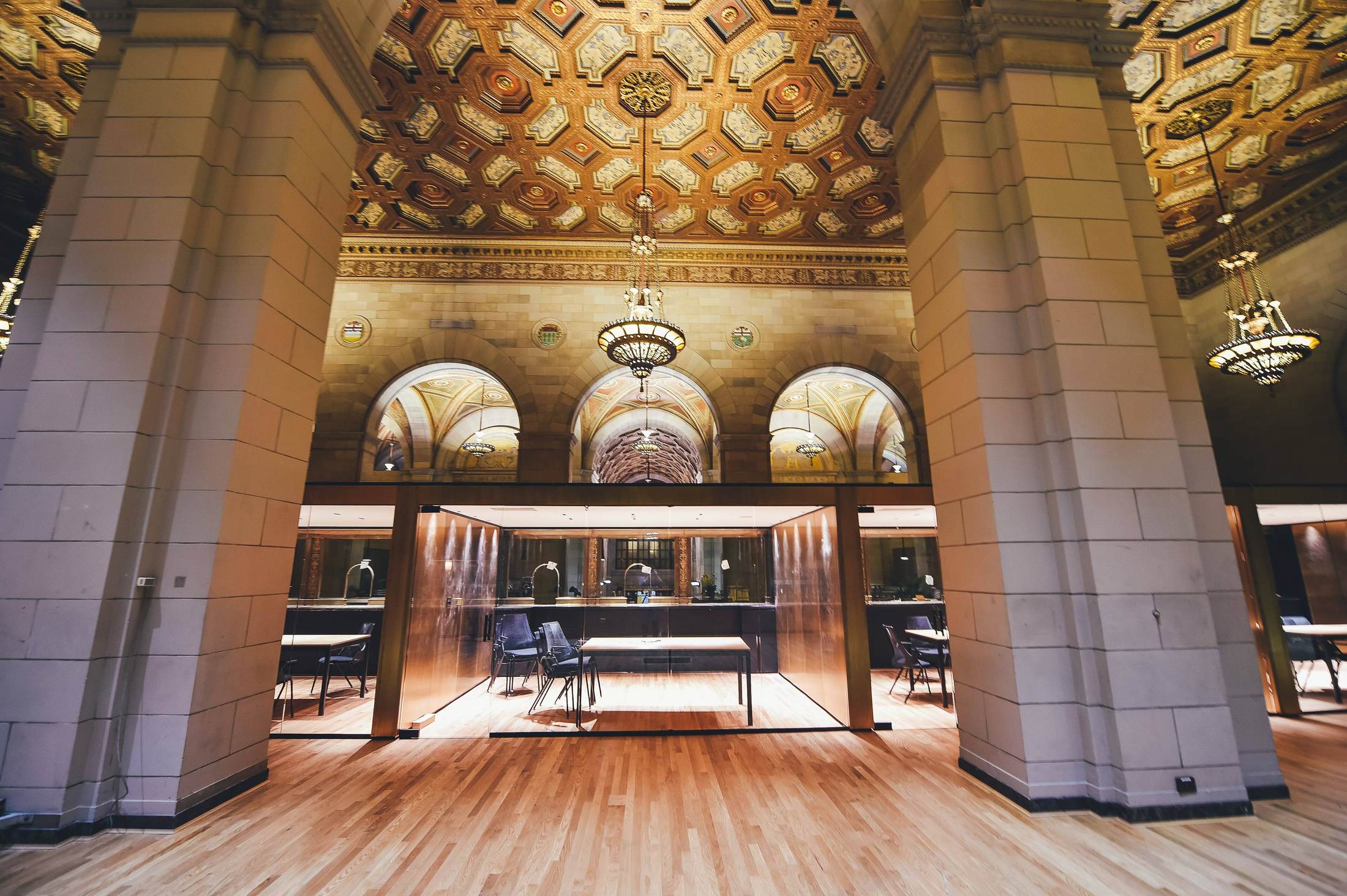 Hard crop of a coffered, gilded vault above a banking hall.