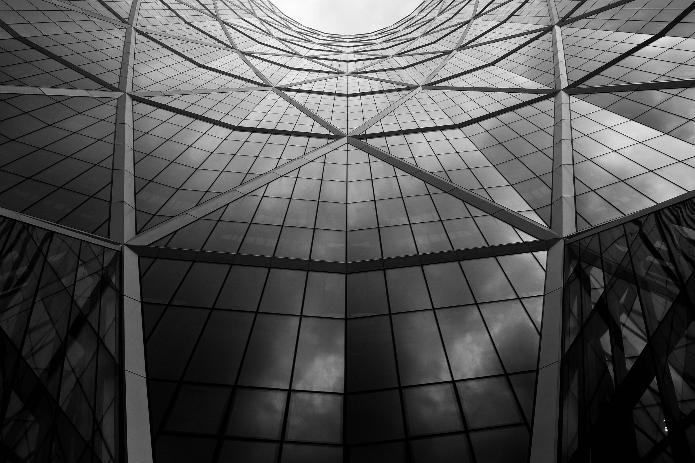 A steel and glass lattice roof photographed from below in monochrome.