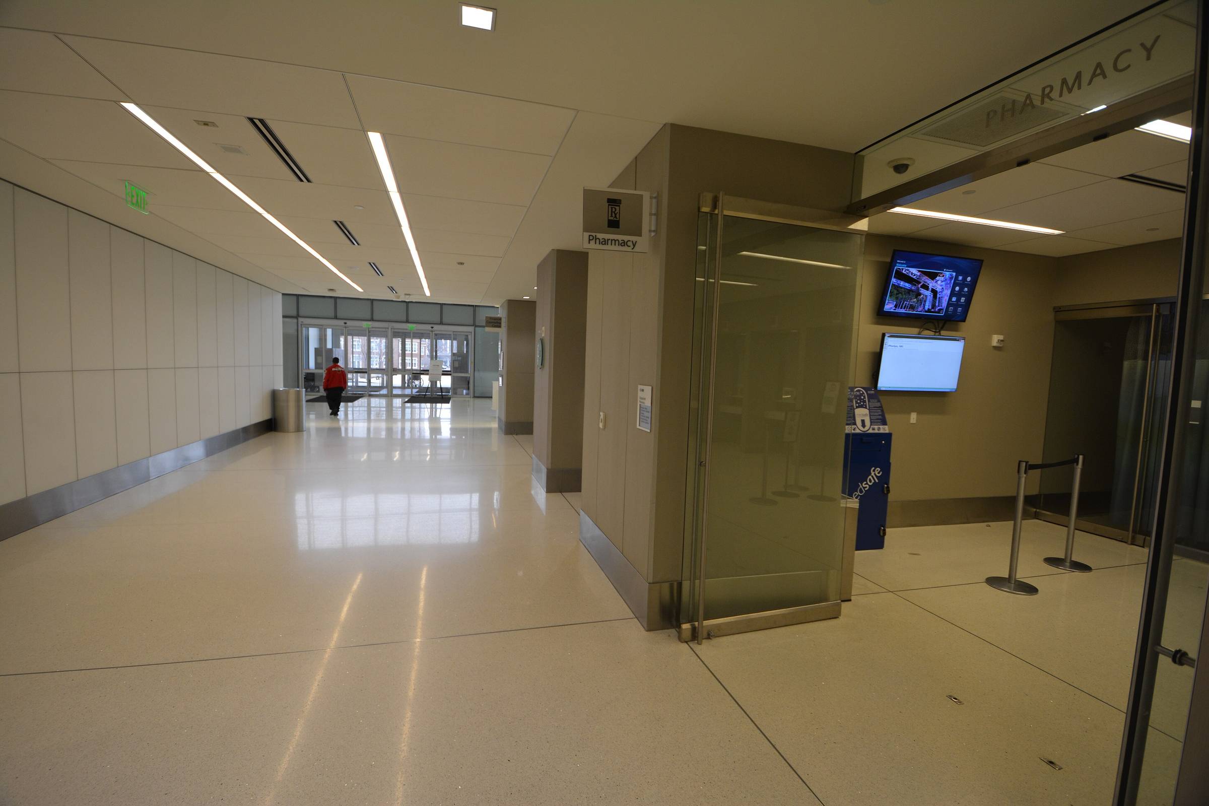 A daylit hospital corridor with signage, photographed straight down its length.