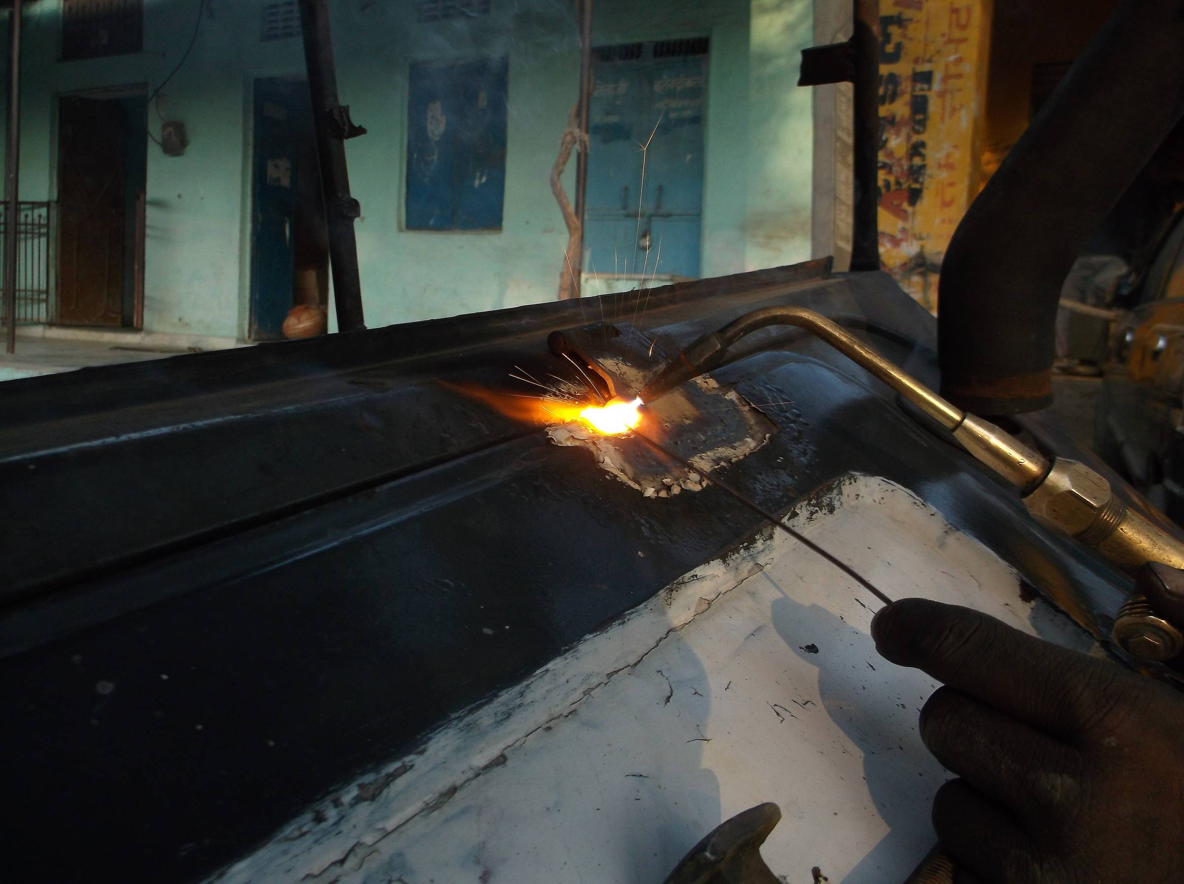 Gloved hands guiding a cutting torch along a steel plate.