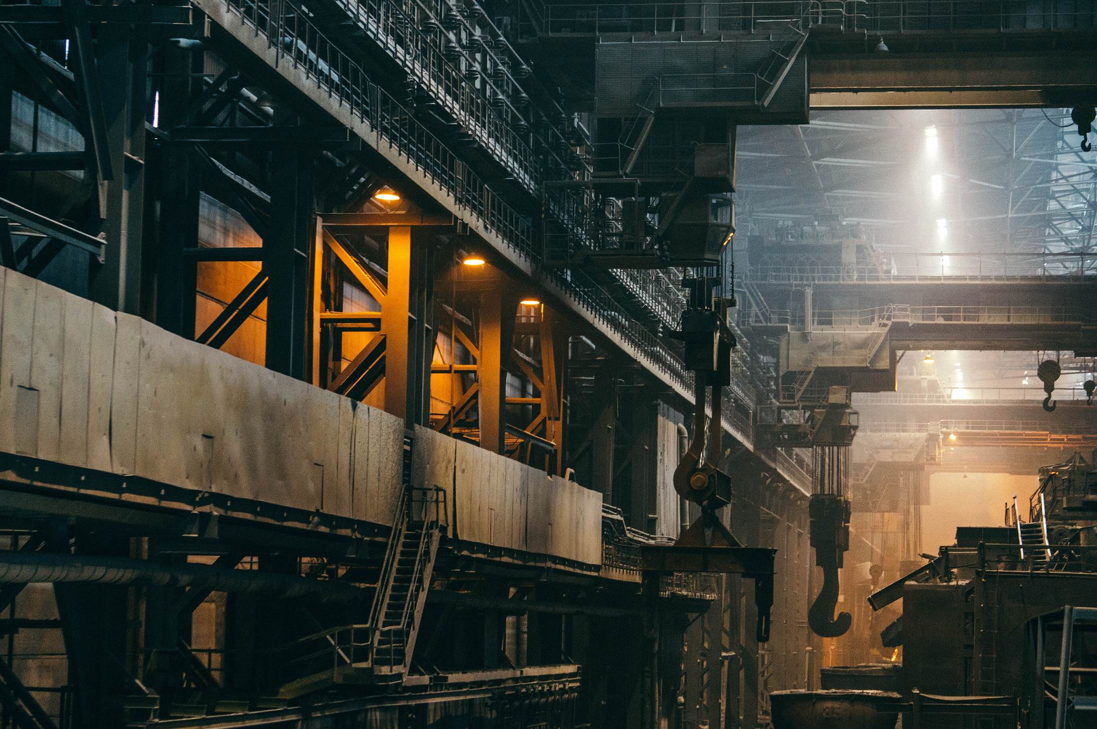 The interior of a heavy manufacturing hall, gantries and ducting lit from high windows.