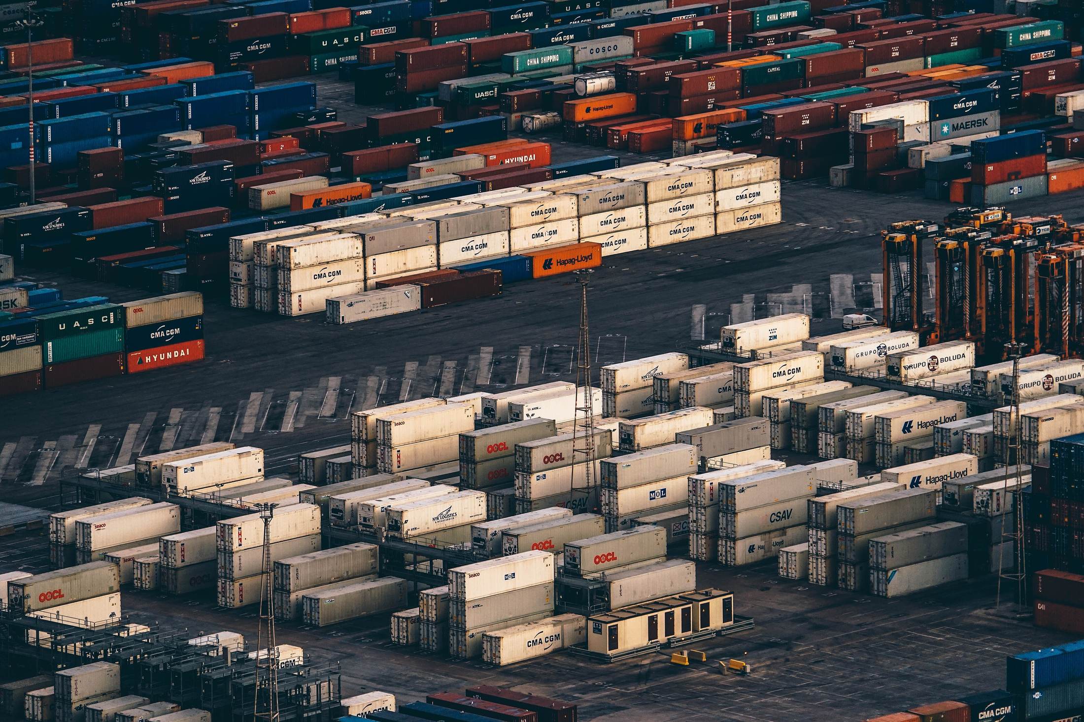 Ordered rows of freight containers stacked in a distribution yard, seen from above.