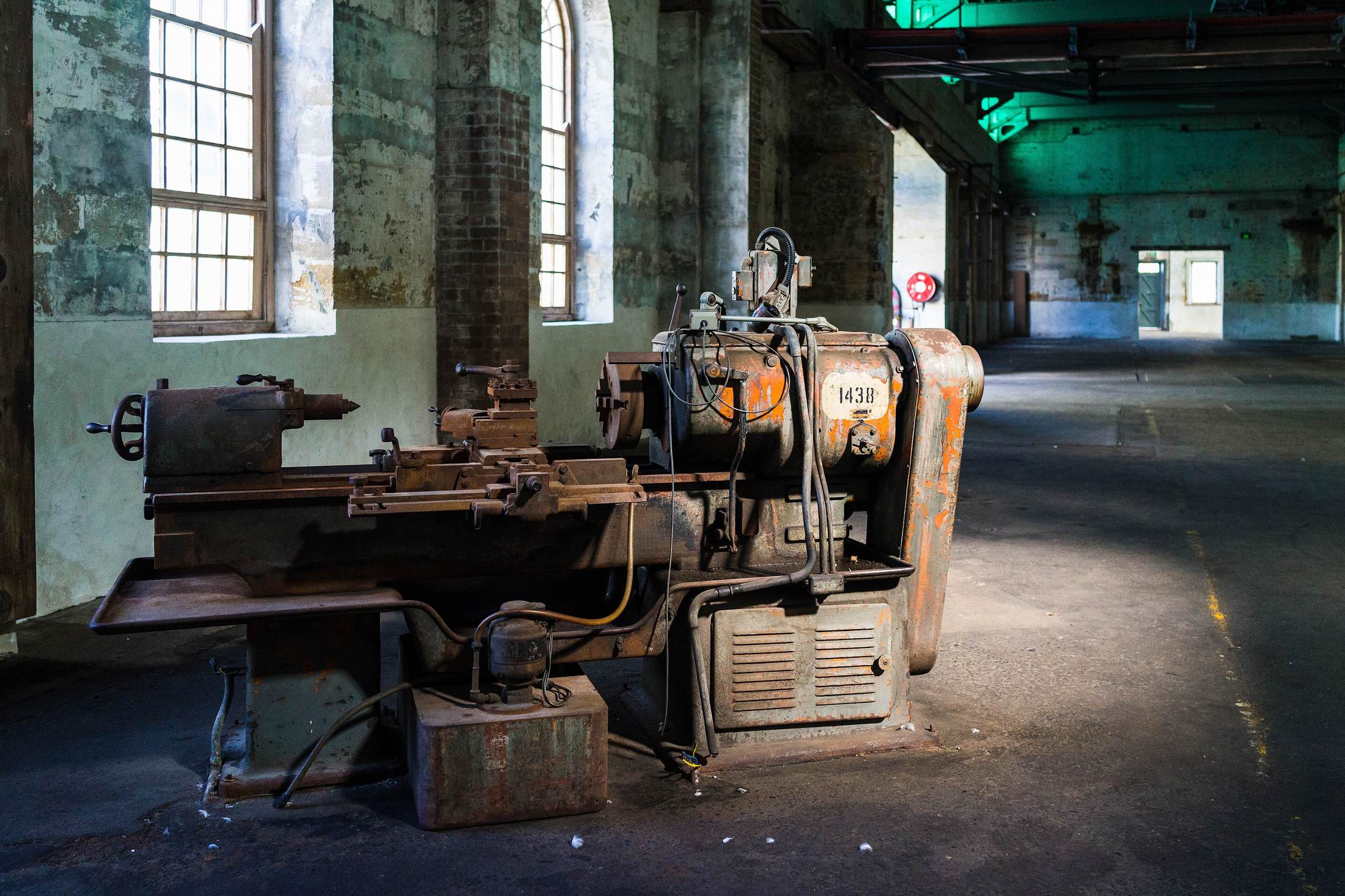 A long machine shop with lathes and mills in a row, lit by high industrial windows.