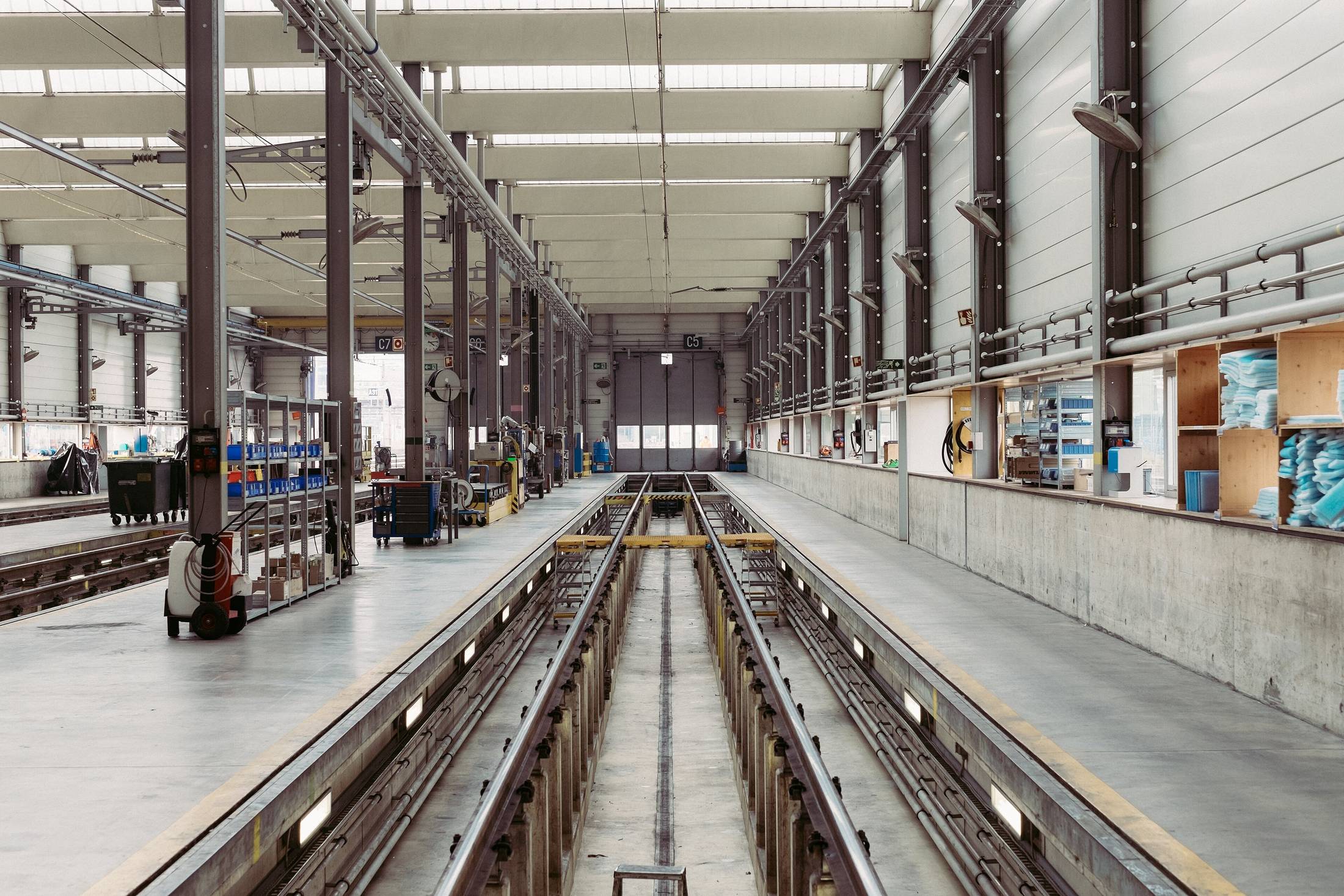 Long interior of a light manufacturing hall, rails running the length of the floor under clerestory windows.